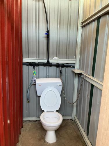 a bathroom with a toilet in a metal building at Redang Campstay in Redang Island