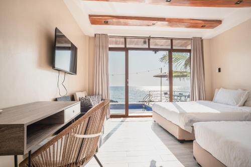 two beds in a room with a view of the ocean at Sofia - Summer Coastal Suites in Bacnotan