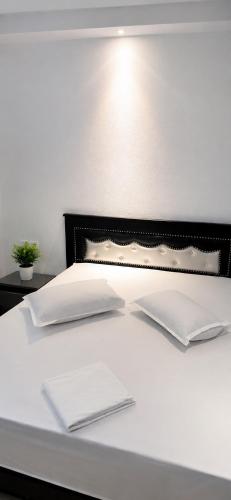 a white bed with two pillows on top of it at Résidence Wissem in Ḩammām al Ghazzāz
