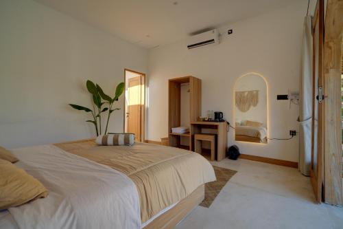 a bedroom with a bed and a table and a mirror at Bellis Garden in Kuta Lombok