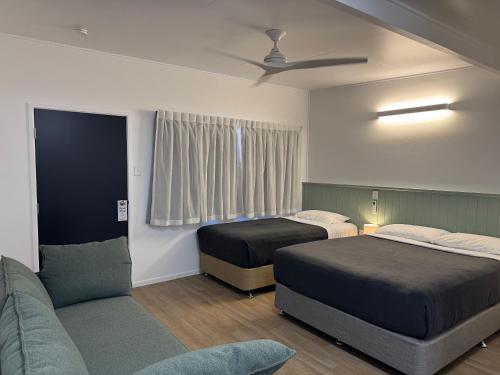 a hotel room with two beds and a couch at Pearly Shell Motel in Bowen