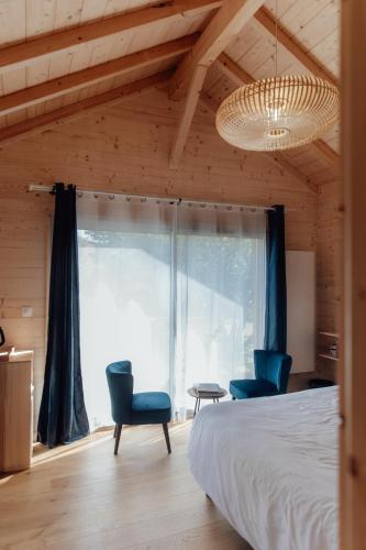 a bedroom with a bed and two blue chairs at Le Clos des Pies in Le Pin