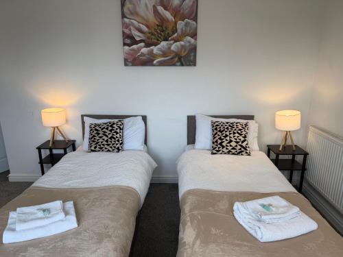 two beds in a room with two lamps at Contractor Accommodation, Free Large Car Park, Sleeps 7 in Kent