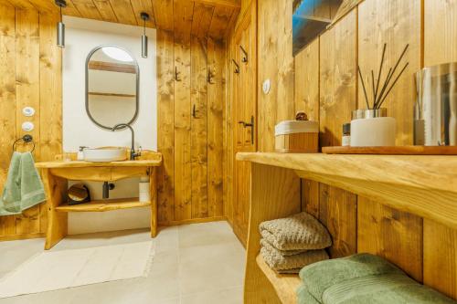 a bathroom with wooden walls and a sink and a mirror at Chalupa Vysoký Potok in Malá Morava