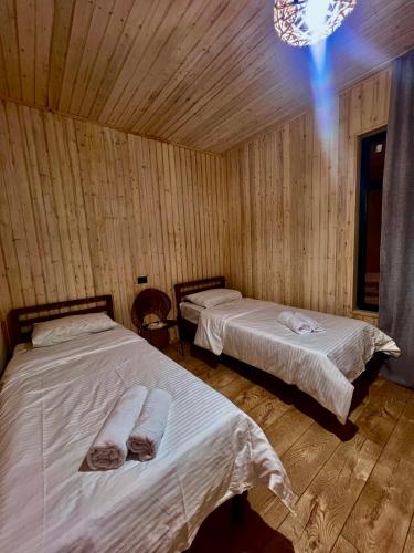 two beds in a room with wooden walls at Marjan bay in Tossor