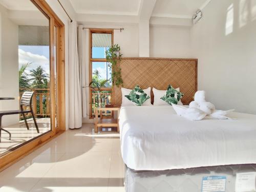 a bedroom with a white bed and a balcony at Sing Siargao in General Luna