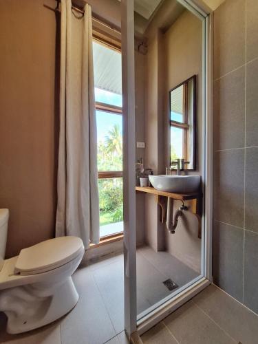 a bathroom with a toilet and a sink and a window at Sing Siargao in General Luna