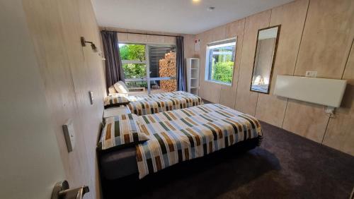 two beds in a room with two windows at Peak Sport Chalet in Wanaka