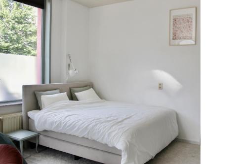 a bedroom with a bed with white sheets and a window at Cozy private suite in Ghent