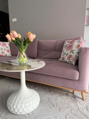 a purple couch with a vase of flowers on a table at APARTAMENT TETRIS - CENTRUM - Garaż in Kielce
