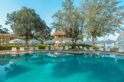 a pool at a resort with chairs and umbrellas at Khaolak Emerald Beach Resort and Spa in Khao Lak