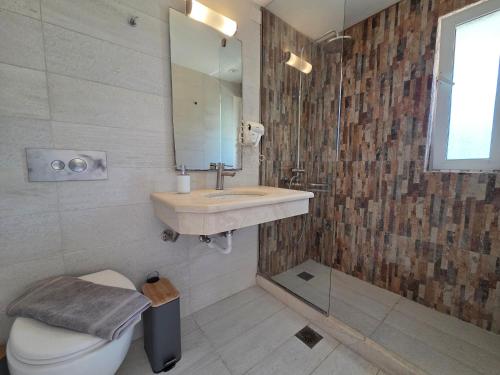 a bathroom with a sink and a toilet and a mirror at Coco's Corfu Apartments in Ipsos