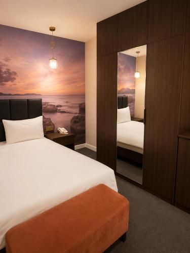a hotel room with two beds and a painting on the wall at Central City Department Hotel in Baku