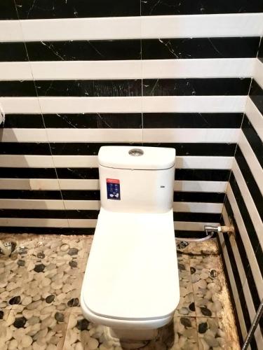 a white toilet in a bathroom with black and white stripes at vista home stay in Lucknow
