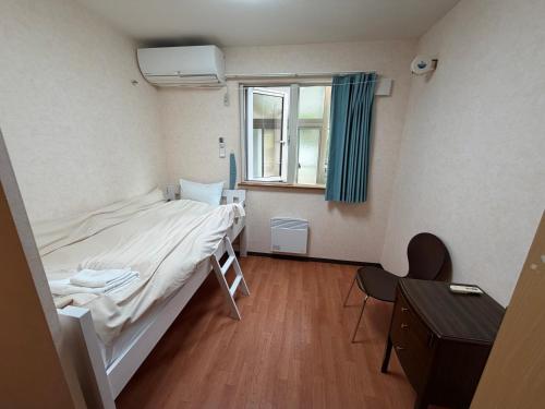 a small room with a bed and a window at Alpine Guesthouse in Furano
