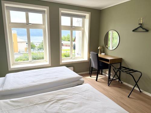 a bedroom with a bed and a desk and two windows at Charming apartment with free parking close to Ålesund center in Ålesund