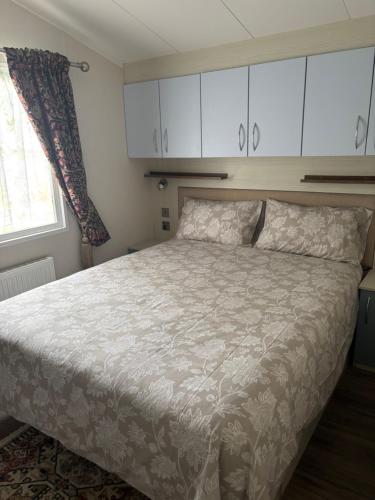 a bedroom with a bed and white cabinets at Luxury 2 Bed Caravan With Decking - Sleeps 4 - at Broadland Sands Park in Lowestoft