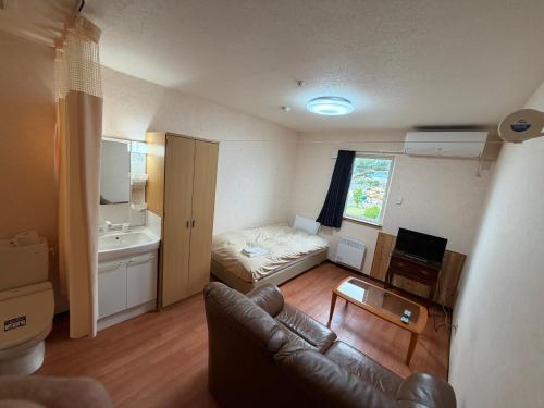 a living room with a couch and a bed at Alpine Guesthouse in Furano