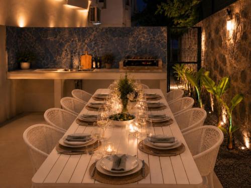 a long white table with chairs and plates and wine glasses at Villa Incir in Kuşadası