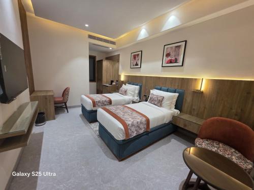 a hotel room with two beds and a chair at Avio Hotel in Chandigarh Airport