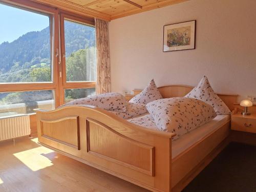 a bedroom with a wooden bed with a large window at Rundblick Gästehaus Schruns Tschagguns by Alpenfeder in Schruns
