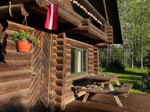 a wooden cabin with a picnic table on a deck at Melderi in Rēzekne