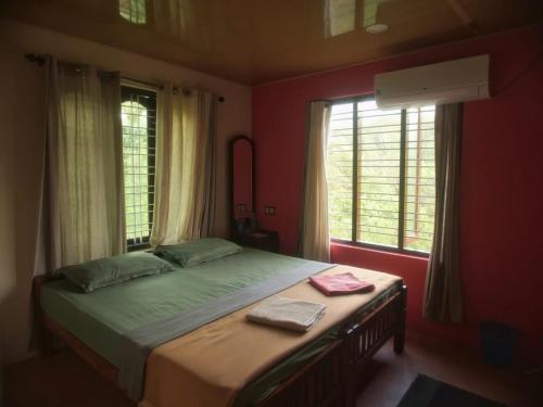 a bedroom with a large bed with two windows at PONMUDI DALE. HOMESTAY in Kallar-Bridge