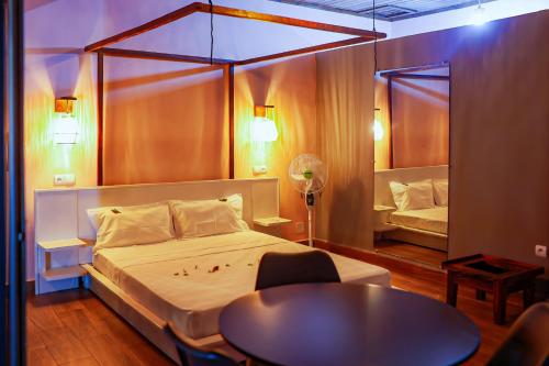 a bedroom with a bed and a table and a mirror at Marionel Hôtel in Ampilahoa