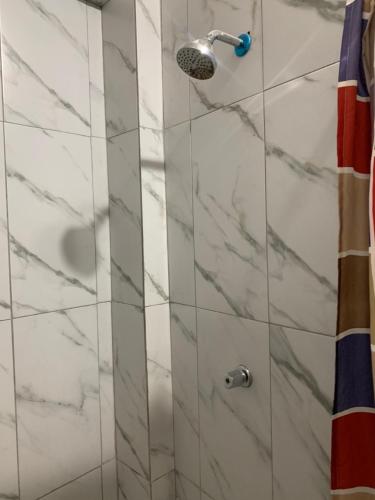 a shower with white marble walls and a shower head at Hostal Belletini in Manta