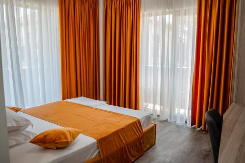 a bedroom with two beds and orange curtains at Wezen in Vama Veche