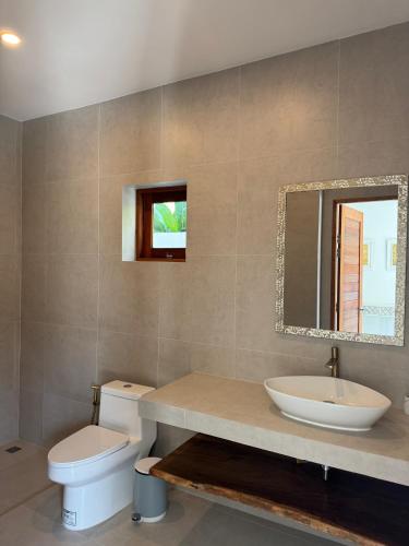 a bathroom with a sink and a toilet and a mirror at Villa Palm Sip Sam in Ko Phangan