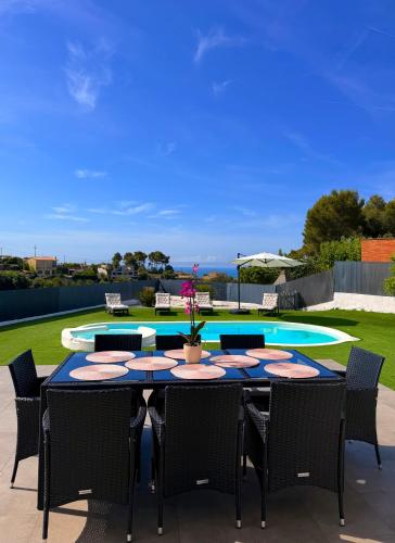 a patio with a table and chairs and a pool at Chillout House with heated pool 29 C Sea & Mountain view in Santa Susanna