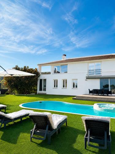 a villa with a swimming pool in front of a house at Chillout House with heated pool 29 C Sea & Mountain view in Santa Susanna