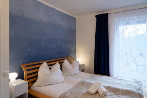 a bedroom with a bed with white pillows and a blue wall at Zirbitzblick in Mönchegg