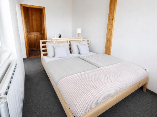 a bedroom with a wooden bed with white sheets and pillows at Csendes Panoráma Apartman in Balatonalmádi