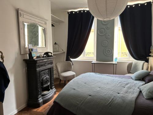 a bedroom with a bed and a fireplace and windows at Chez Anne in Fécamp