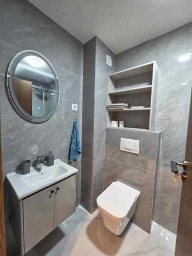 a bathroom with a toilet and a sink and a mirror at Eclipse Luxury Suite in Šušanj