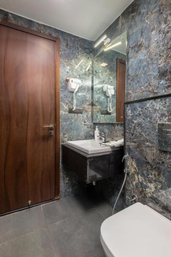 a bathroom with a sink and a wooden door at Hotel Altitude Coorg in Madikeri