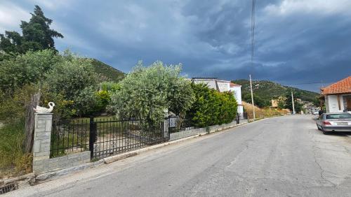 an empty street with a fence and a car on the road at Olive Garden Estate in Elevtheraí
