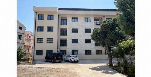 a building with two cars parked in a parking lot at Big Family apartment - 3BR in Budva