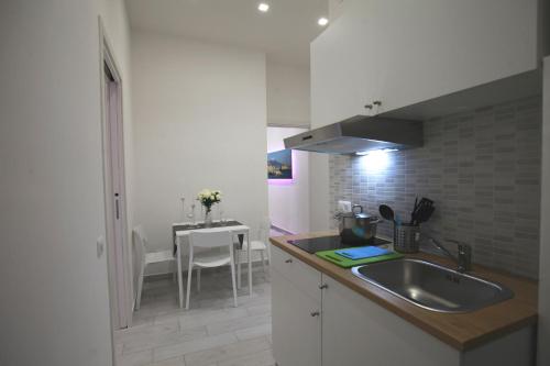 eine weiße Küche mit einem Waschbecken und einem Tisch in der Unterkunft B&B Il Porto in Neapel