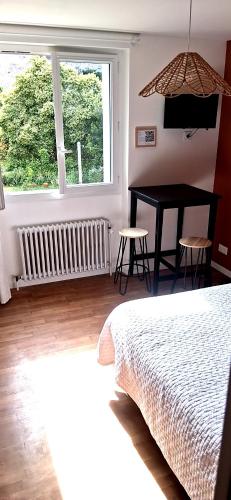 a bedroom with a bed and a table and a window at Logement entier RDC quartier historique Parthenay in Parthenay