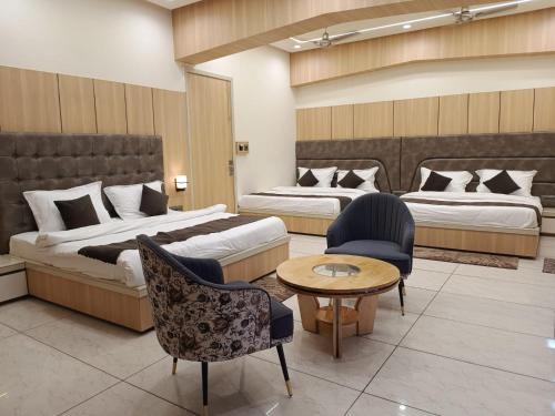 a hotel room with two beds and a table and chairs at Hotel Jai Palace in Ajmer