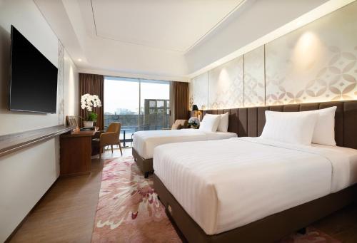 a hotel room with two beds and a flat screen tv at Atria Hotel Malang in Malang