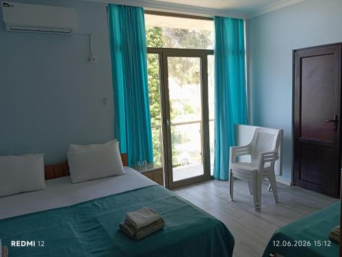 a bedroom with a bed and a chair and a window at Hotel Marina in Shekhvetili
