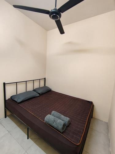 a bed in a room with a ceiling fan at Homestay Che Wan Satu in Kuantan