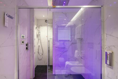 a purple bathroom with a toilet and a glass door at Monaco Suites Hotel in Lignano Sabbiadoro