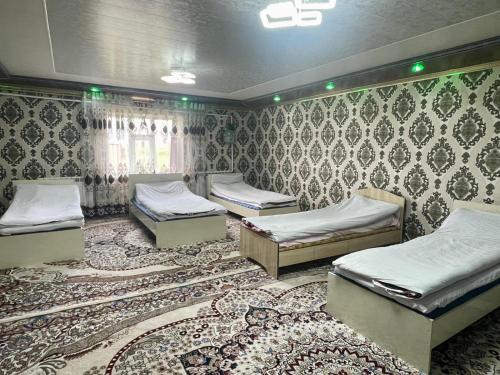 a room with three beds and a rug at Ali guest house in Sary-Mogul