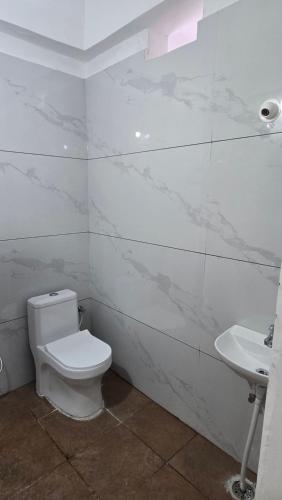 a white bathroom with a toilet and a sink at VRK Comfort in Mysore