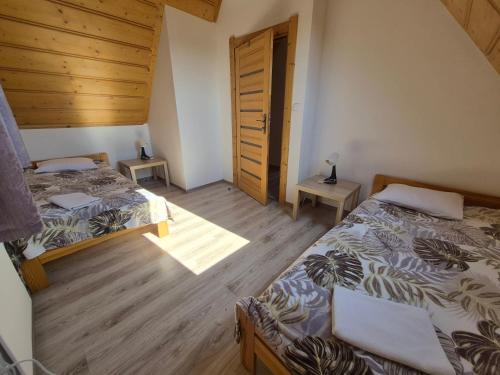 a bedroom with two beds and a wooden floor at NowiNowe Domki in Dzianisz